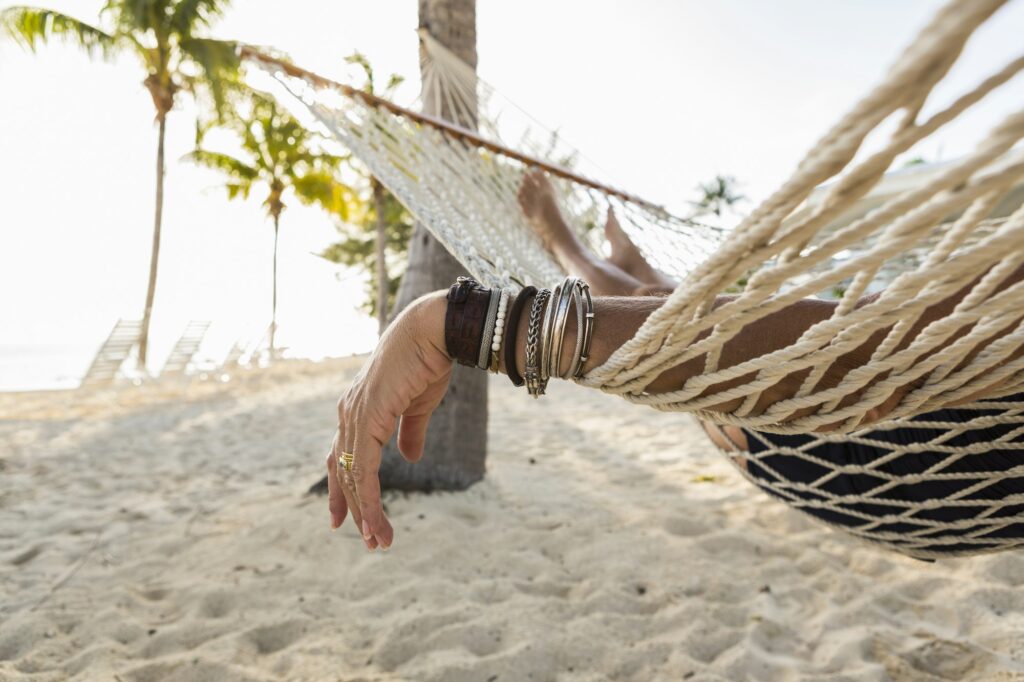 close up of woman's arm and bracelets, resting in hammock